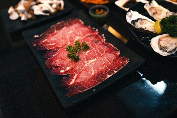 Sliced beef shabu in a black plate in a restaurant