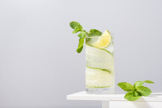 Refreshing cocktail with lime and cucumber served on white table