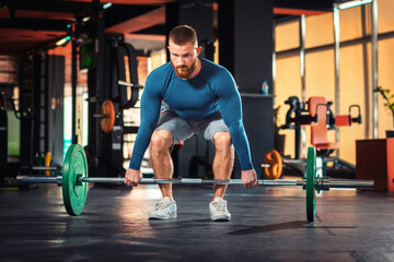 Barbell squats. A young bearded athletic man trains in the gym, lifting a barbell. The concept of fitness and training