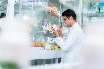 A male pharmacist holding prescription checking medicine in pharmacy or drugstore, Medical healthcare concept.