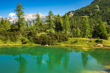 Obraz premium People relax on the shore of the mountain lake Märchensee, literally fairy tale lake, on the Tauplitzalm plateau, Tauplitz, Ausseer Land, Austria
