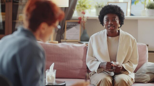 Upset African American woman crying and complaining to female psychologist during counseling session