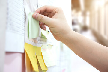 Commenting. Brainstorm or workshop. man's hand sticks a post-it note on the board.