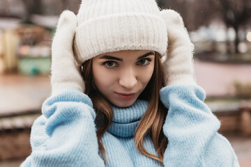 Young pretty smiling woman looking at the camera dressed knitted hat mittens. Cold weather, winter holidays, travel. New Year Christmas fair decorations, Valentines Day concept copy space