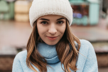 Young pretty smiling woman looking at the camera dressed knitted hat mittens. Cold weather, winter holidays, travel. New Year Christmas fair decorations, Valentines Day concept copy space