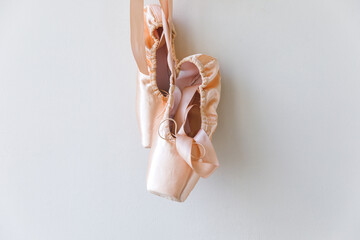 New pastel beige ballet shoes with satin ribbon isolated on white background. Ballerina classical pointe shoes for dance training. Ballet school concept, Copy space