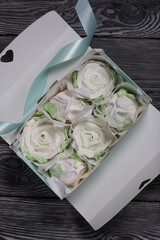 Homemade marshmallow in a gift box. Zephyr roses.  Marshmallow roses.  On black pine boards. Close-up shot.