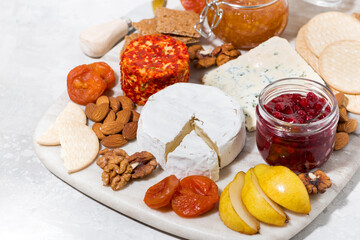 assortment of delicacy cheeses and snacks on board, top view