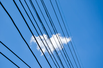 Fototapeta na wymiar A piece of white floating cloud through the electric wires.