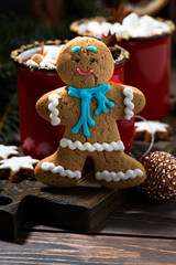 gingerbread man cookies and hot chocolate on wooden background, vertical closeup