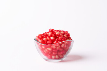 Pomegranate fruit seeds in a glass bowl on a white background