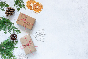 Minimalism style Christmas composition with gift box in craft paper and fresh fir tree branches on white stone background long banner format. Plastic free zero waste Christmas decorations.