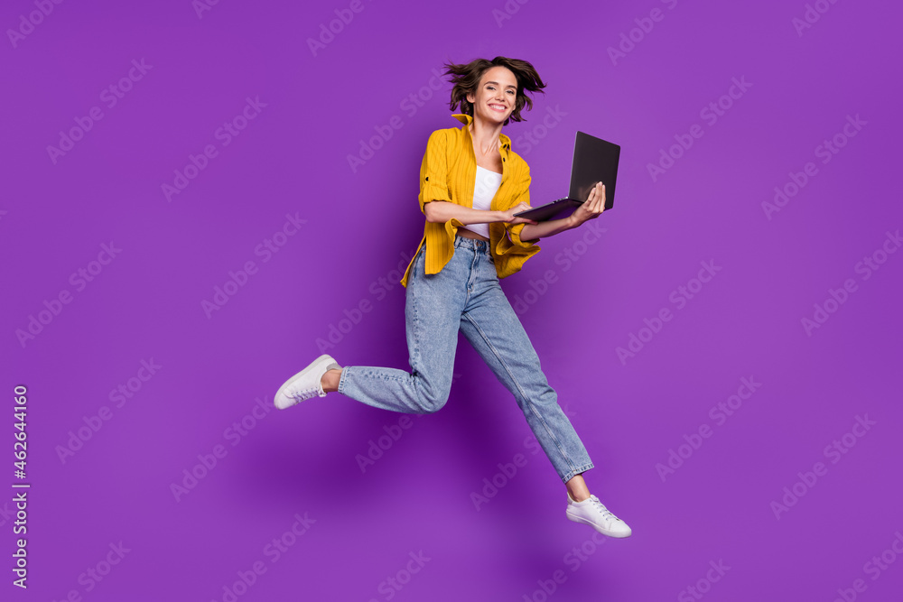 Sticker Photo of sweet charming young lady wear yellow shirt jumping high typing modern gadget smiling isolated violet color background