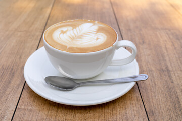 Latte coffee or cappuccino coffee in white cup with beautiful tree latte art on wooden table.