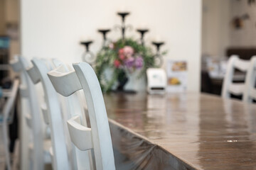 Set of white chairs and wooden dining table in luxury style restaurant. Interior decoration furniture object. Close-up and partial focus at chair's part.