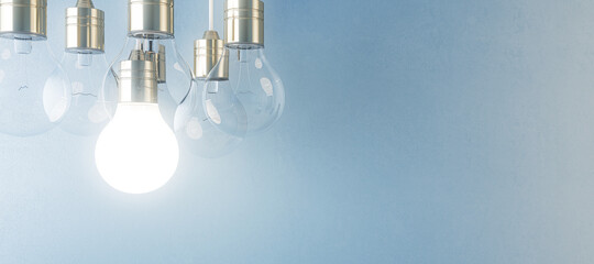 Glowing light bulb on blurry wide blue wall background. Idea, innovation, solution and invention...