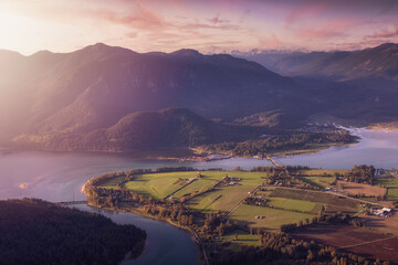 Fototapeta premium Aerial View of Fraser Valley with Canadian Nature Mountain Landscape Background. Colorful Sunset Sky Art Render. Harrison Mills near Chilliwack, British Columbia, Canada.