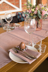 Delicate table setting for Easter. Fork, knife napkins, glasses and a chocolate egg. Happy Easter