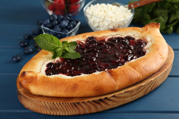 Delicious sweet cottage cheese pastry with cherry jam on blue wooden table, closeup