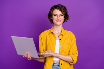 Portrait of attractive cheerful girl holding using laptop web startup isolated over bright violet...