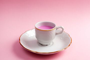 Close-up of coffee cup and plate with rose coffee or tea. Pink background. Minimalism