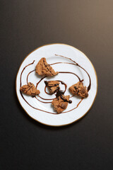top view of plate with pieces of chocolate chip cookies with syrup on black background