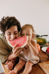 Mother and child daughter are eating watermelon Healthy food at home. Happy family in the kitchen.  