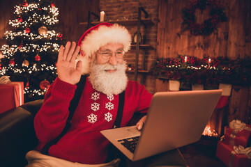 Portrait of attractive pensioner retired Santa waving hi congrats using laptop festal at home loft...