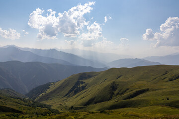 A panoramic view on high Caucasus mountains in Georgia. There are high, snowcapped peaks in the back. Lush pasture in front. Idyllic landscape. Calmness and meditation. Natural remedy. Few clouds