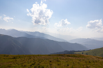 A panoramic view on high Caucasus mountains in Georgia. There are high glaciers in the back. Thick clouds above the sharp peaks. Lush pastures on the sides. Barren peaks.  Idyllic landscape. © Chris