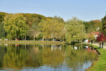 Fototapeta na wymiar Le lac de Genval dans un cadre bucolique avec ses villas et immeubles à appartements dissimulés dans la nature luxuriante qui l'entoure en automne