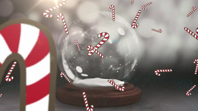 Candy cane icons falling over shooting star spinning around snow globe against grey background