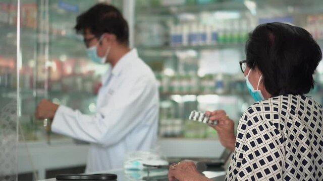 A male pharmacist selling medications to senior patient.
