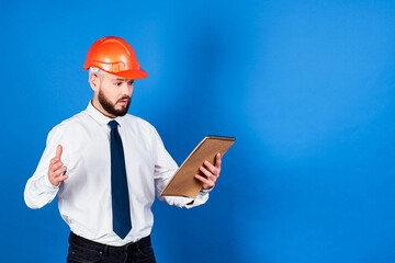 A surprised, attractive male architect with a helmet on his head.