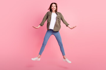 Fototapeta na wymiar Full length photo of funny brunette hairdo lady jump wear green shirt jeans sneakers isolated on pink color background