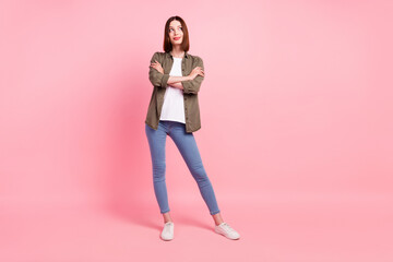 Full size photo of cute brunette hairdo millennial lady crossed arms look empty space wear green shirt jeans isolated on pink color background