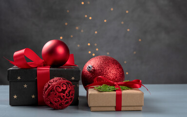 Christmas composition. Christmas presents, red Christmas balls, fir branches on a gray background with fairy lights. Top view, copy space