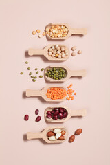 Vegan protein source. Beans, peas, chickpeas, lentils, mung bean, peanut in wooden spoon on beige background.