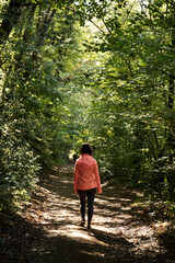 unrecognizable woman walking into the forest - healthy lifestyle concept