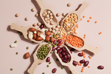 Vegan protein source. Beans, peas, chickpeas, lentils, mung bean, peanut in wooden spoon on beige background.
