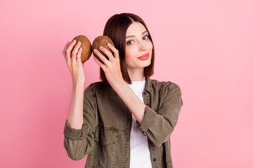 Photo of think brunette hairdo millennial lady hear coconuts wear khaki shirt isolated on pink...