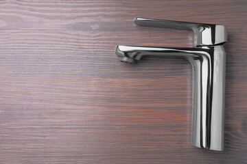 Single handle water tap on wooden table, top view. Space for text