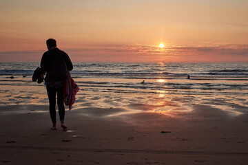 A rear view of a lady at the beach enjoying the scenic sunset