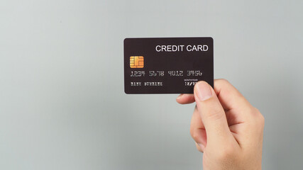 Hand is holding black credit card isolated on grey background.
