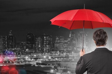 Insurance concept, Businessman holding red umbrella on falling rain on city background