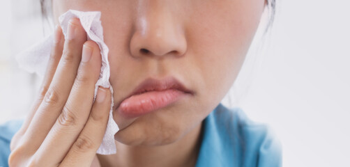 A woman is using tissue paper to wipe her face violently.
