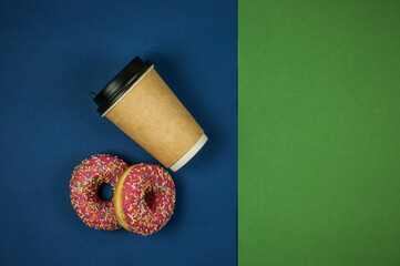  paper coffee cup with two doughnuts lie on a green and blue background. A place to copy. Top view. Close-up, copy space, background.