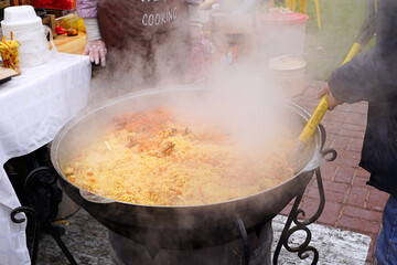 Cooking pilaf at a street food festival. The cook mixes the pilaf with a shovel. Kazan, September 2021 - 462657735