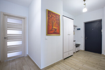 The interior of the corridor in a two-room apartment with a kitchen, in light colors