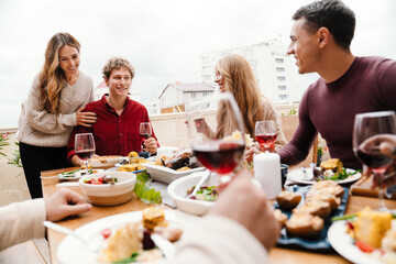 Multiracial happy friends drinking wine during thanksgiving dinner